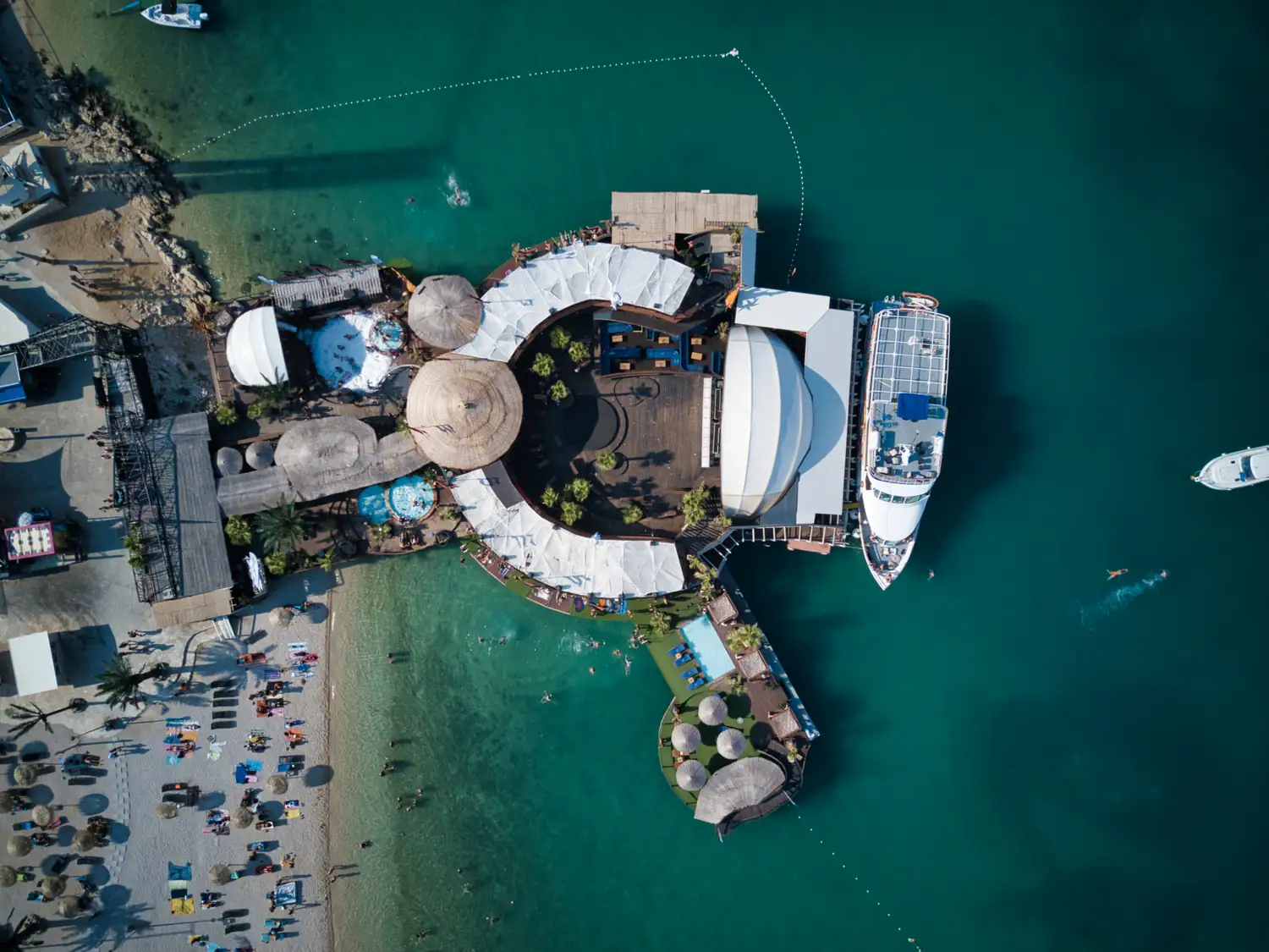 Luftaufnahme einer Uferanlage mit Schiff am türkisfarbenen Wasser