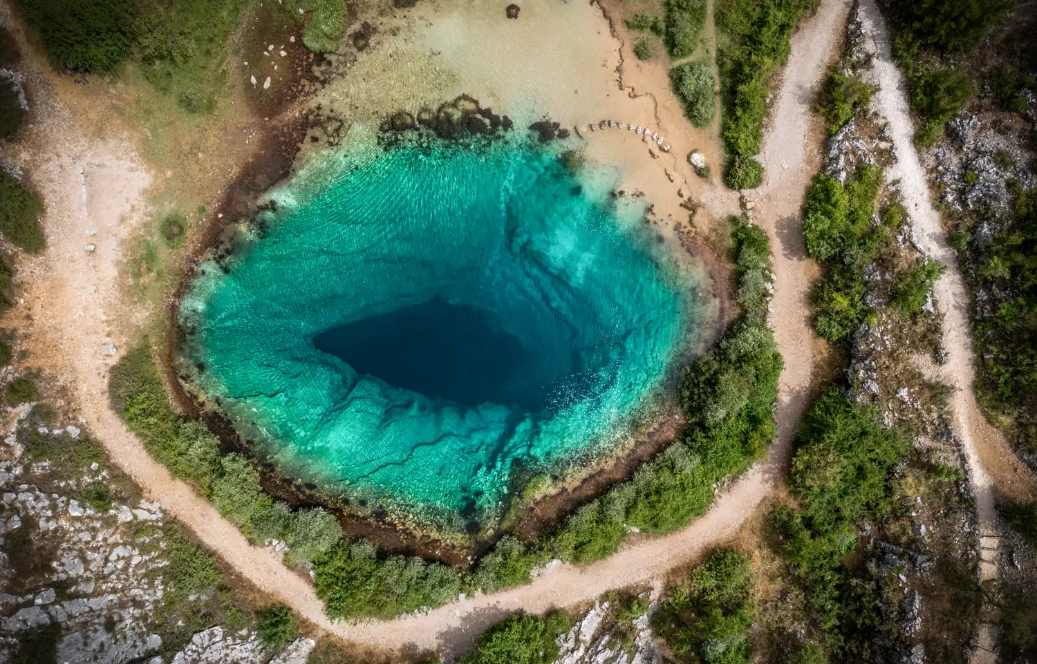 Blaues Loch in einer Karstlandschaft von oben