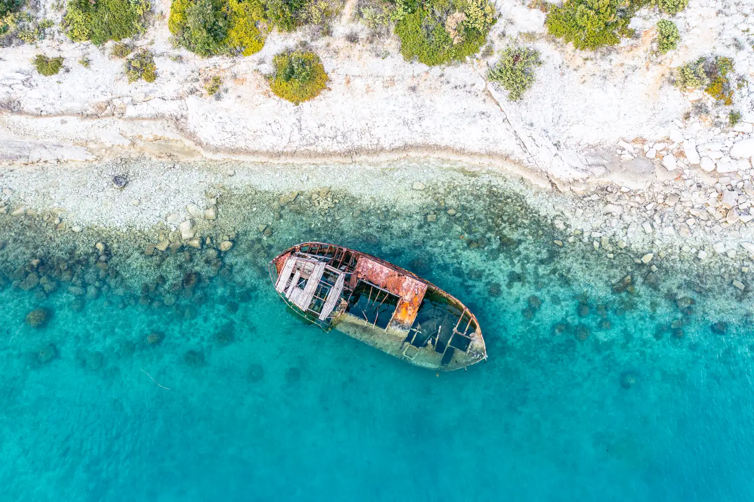 Gestrandetes Schiffswrack im türkisfarbenen Wasser von oben