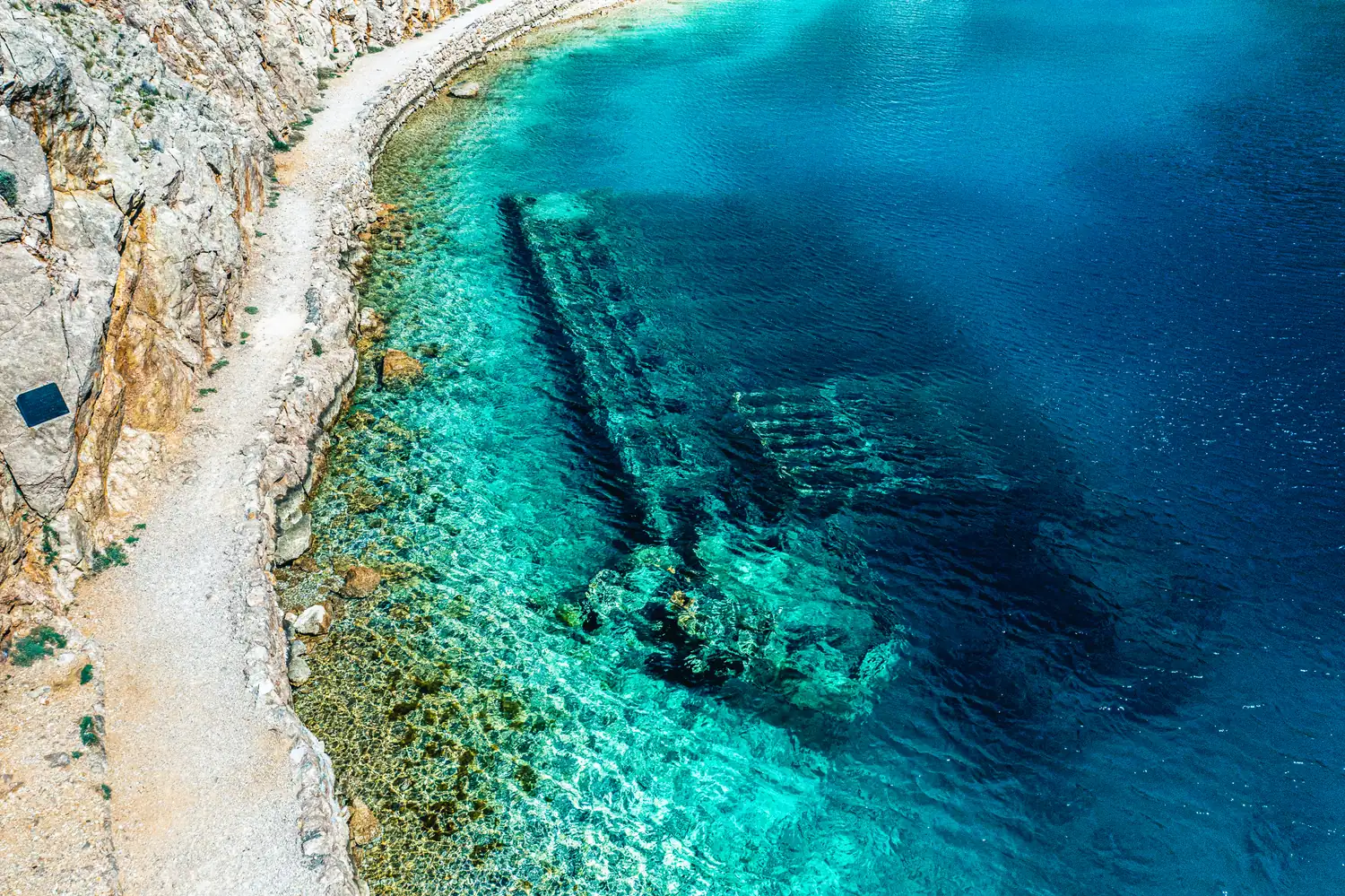 Versunkenes Wrack unter Wasser an einer Felsküste