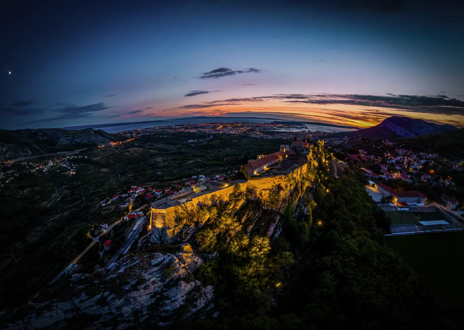 Panorama einer Festung über einem Ort bei Sonnenuntergang