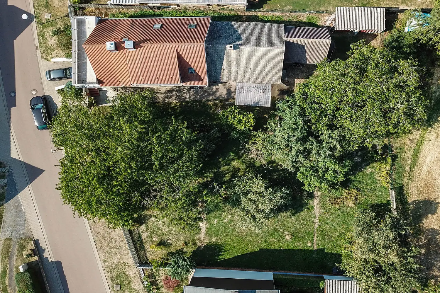 Senkrechte Luftaufnahme eines Hauses mit Garten an einer Straße