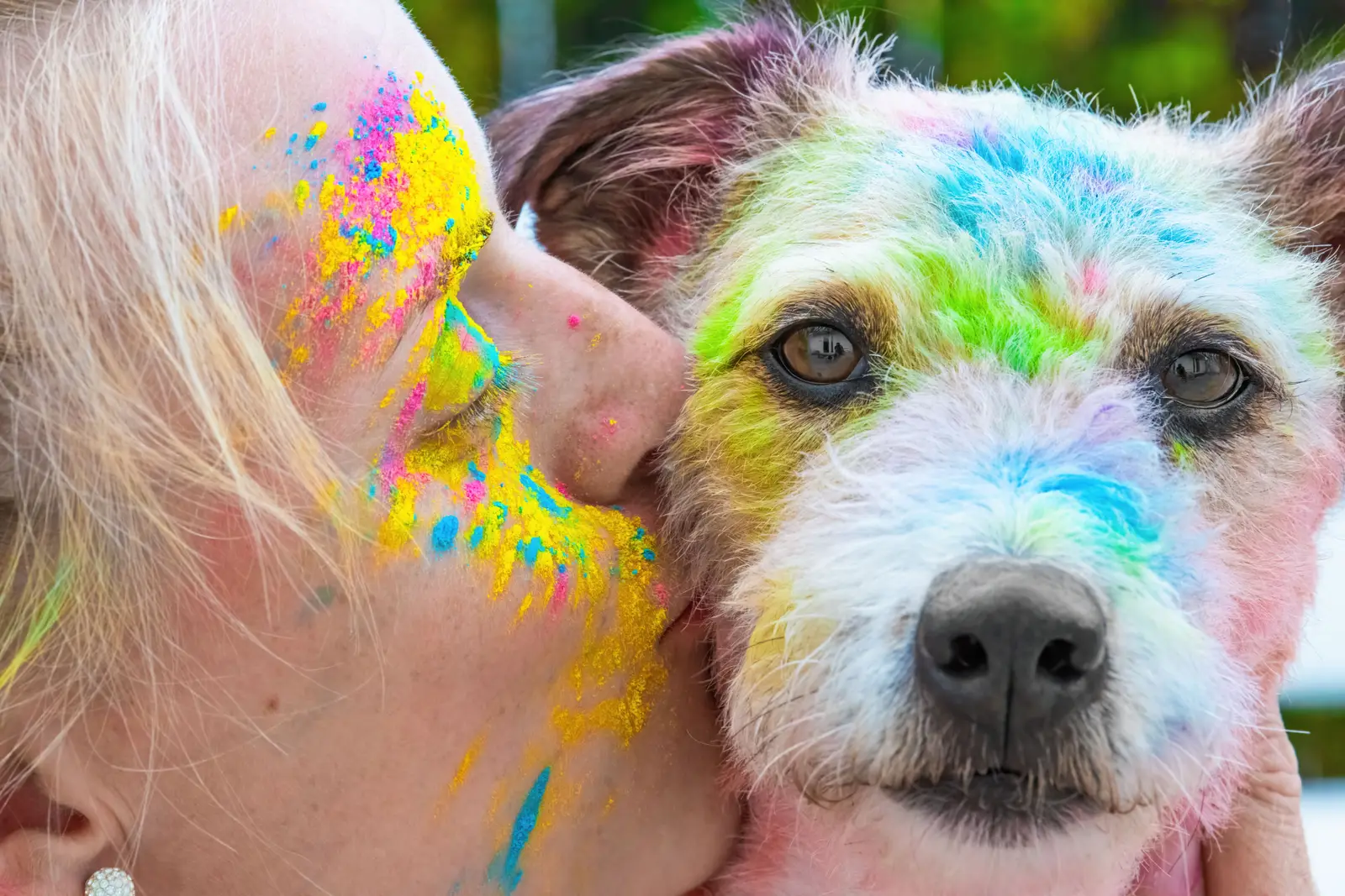 Frau und Hund mit buntem Farbpulver im Gesicht