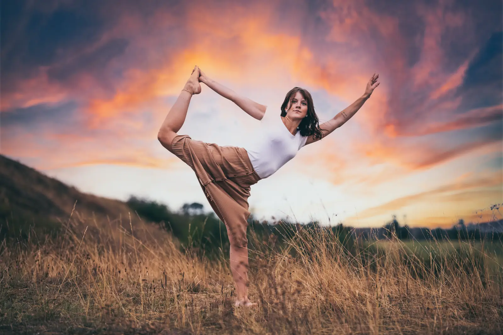 Frau in Yogapose vor einem Abendhimmel