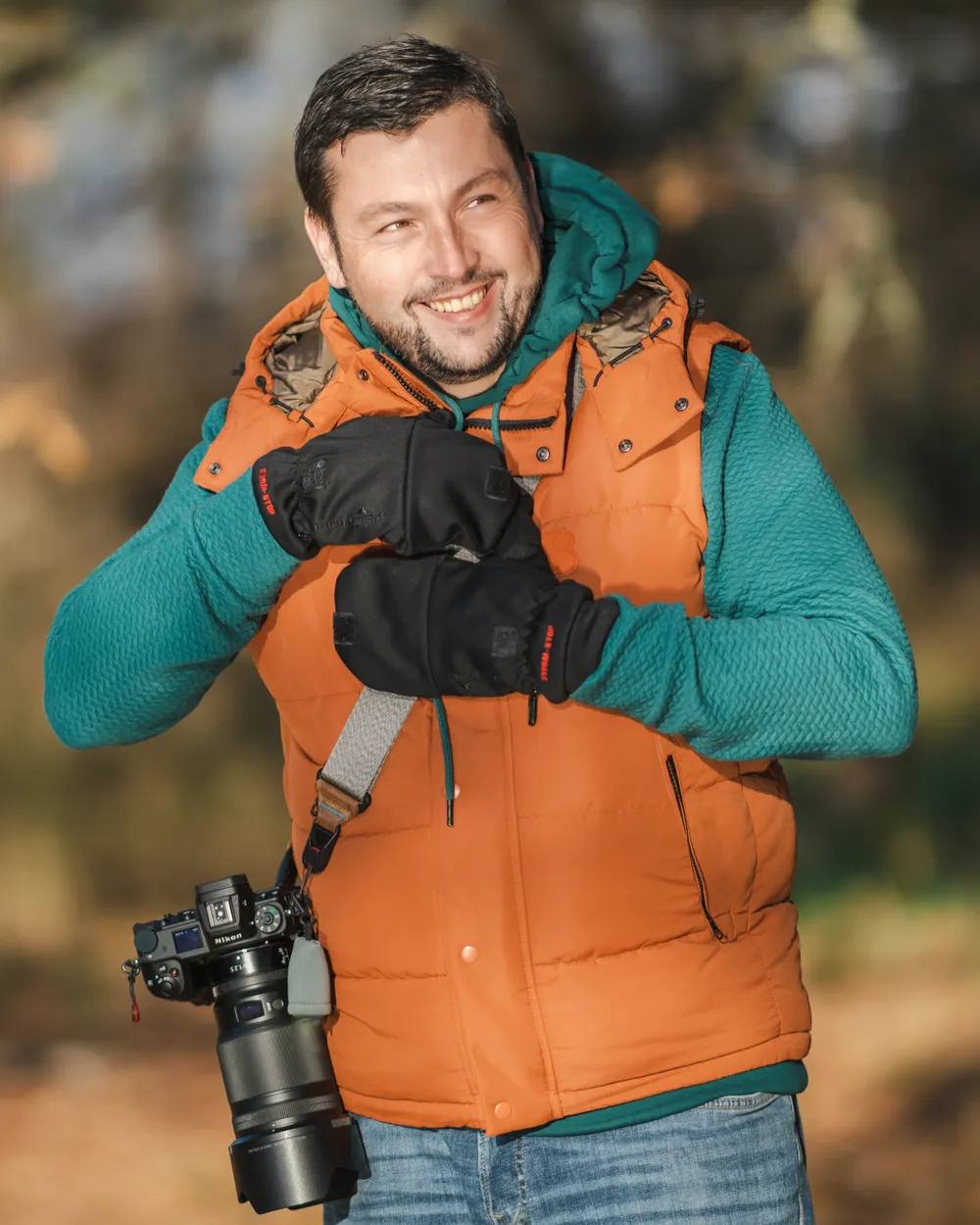 Bertram Plischke lächelt in oranger Weste, eine Nikon-Kamera hängt an seiner Schulter