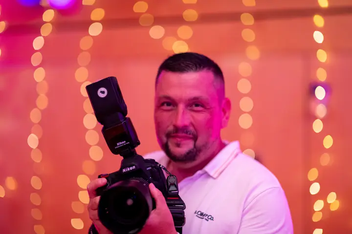 Fotograf mit Kamera in einem bunt beleuchteten Raum
